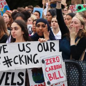 Protestors in New Zealand holds signs for climate justice.