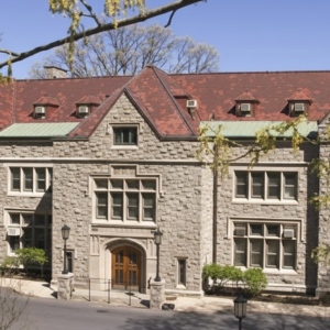 Stone building with red roof surrounded by trees.