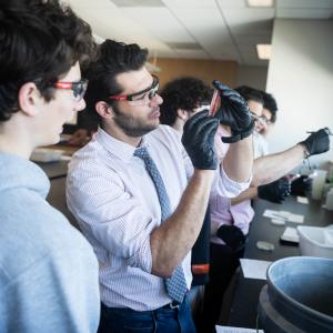 Lorenzo Servitje holds a pipette in a lab and examines it.