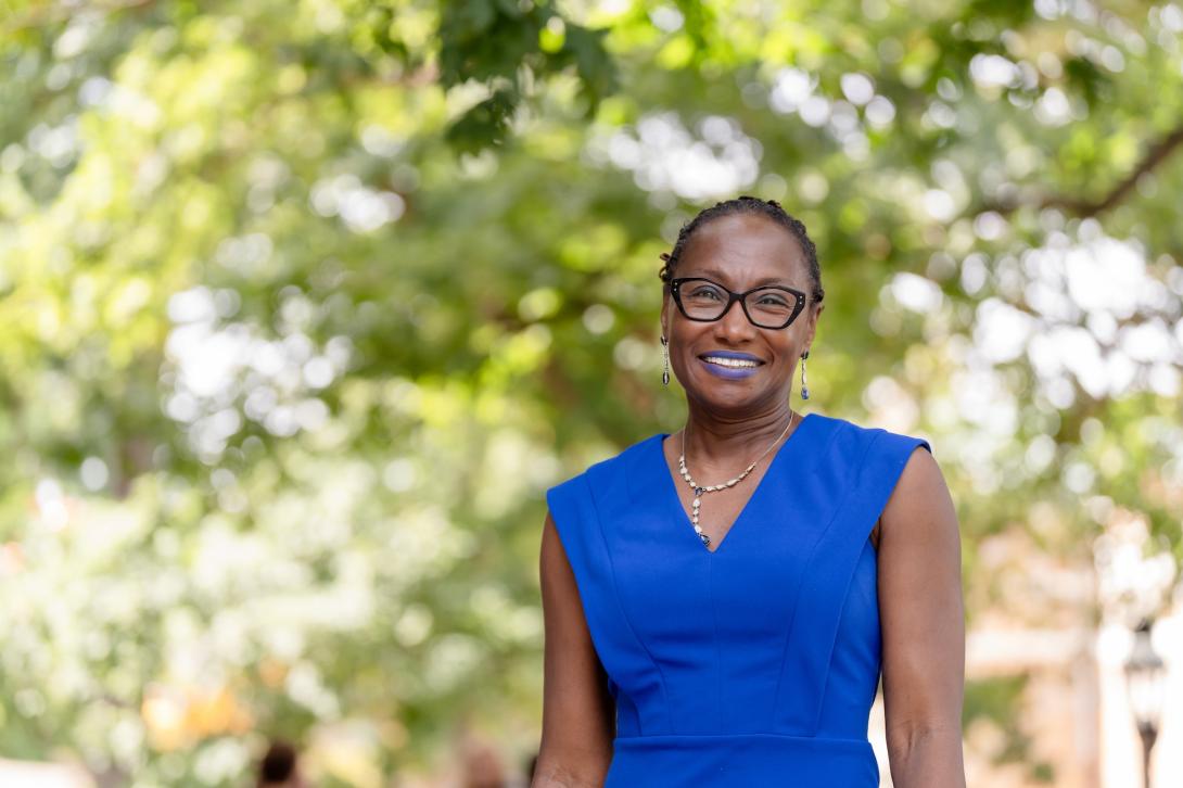 Simone A James Alexander poses for a photo outside wearing a blue dress.