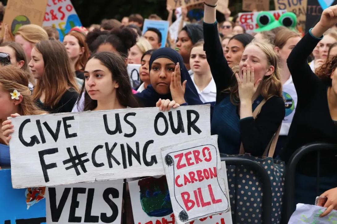 Protestors in New Zealand holds signs for climate justice.
